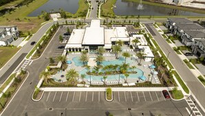 Vista aerea di un hotel con piscina centrale, circondato da palme e lettini.