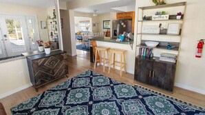 A modern kitchen with a central island, wooden bar stools, and a patterned rug. - LakeFront Sunrise Cottage (Sebring)