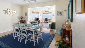 A dining area with a table set for four, surrounded by white chairs with blue cushions. - LakeFront Sunrise Cottage (Sebring)