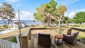 Une terrasse en bois, meublée de mobilier en osier, avec vue sur l’océan.