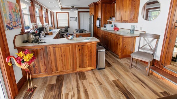 Une cuisine spacieuse dotée de meubles en bois, d’un îlot central et d’un coin repas avec une chaise.