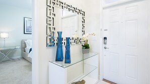 A modern bathroom with a glass vanity, blue vases, and a decorative mirror.