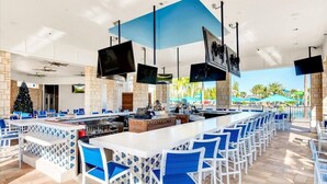 A bar area with a long counter, blue chairs, and a Christmas tree. - Last Minute Disney Getaway! Private Pool & Themed Bedrooms. Book Now! #66193 (Orlando)