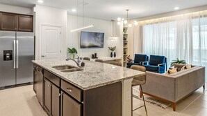 A modern kitchen with a central island, built-in appliances, and a dining area with a sofa and chairs. - Last Minute Disney Getaway! Private Pool & Themed Bedrooms. Book Now! #66193 (Orlando)