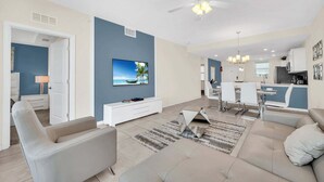 A modern living room with a TV, sofa, and dining area. - Last Minute Disney Getaway! Themed Bedrooms & Private Balcony. Book Now! #113577 (Orlando)