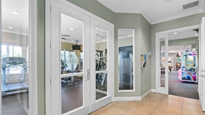A hallway with a treadmill, exercise equipment, and a children's play area. - Last Minute Disney Getaway! Private Pool & Themed Bedrooms. Book Now! #66159 (Orlando)