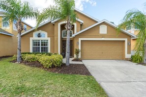 A two-story house with a garage, a front porch, and a well-maintained lawn.