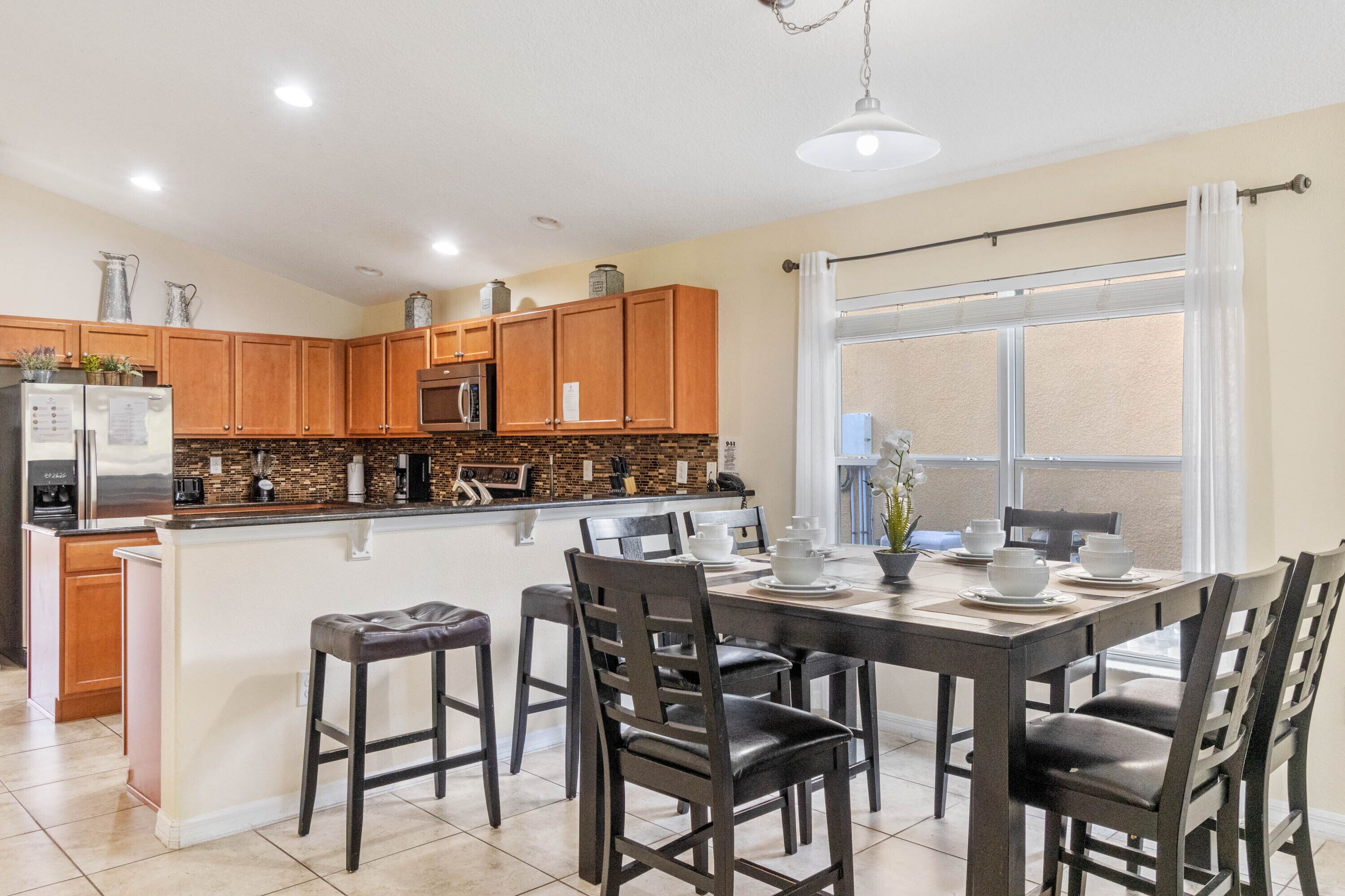 A modern kitchen with wooden cabinets, a central island, and a dining area with a table and chairs.