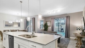 A modern kitchen with a central island, built-in dishwasher, and pendant lighting. - Last Minute Disney Getaway! Private Pool & Themed Bedrooms. Book Now! #65921 (Orlando)