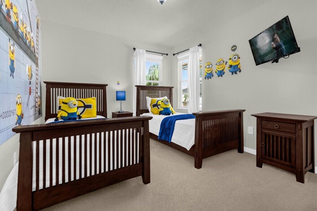 A bedroom with two wooden beds, a nightstand, a dresser, and a television on the wall.