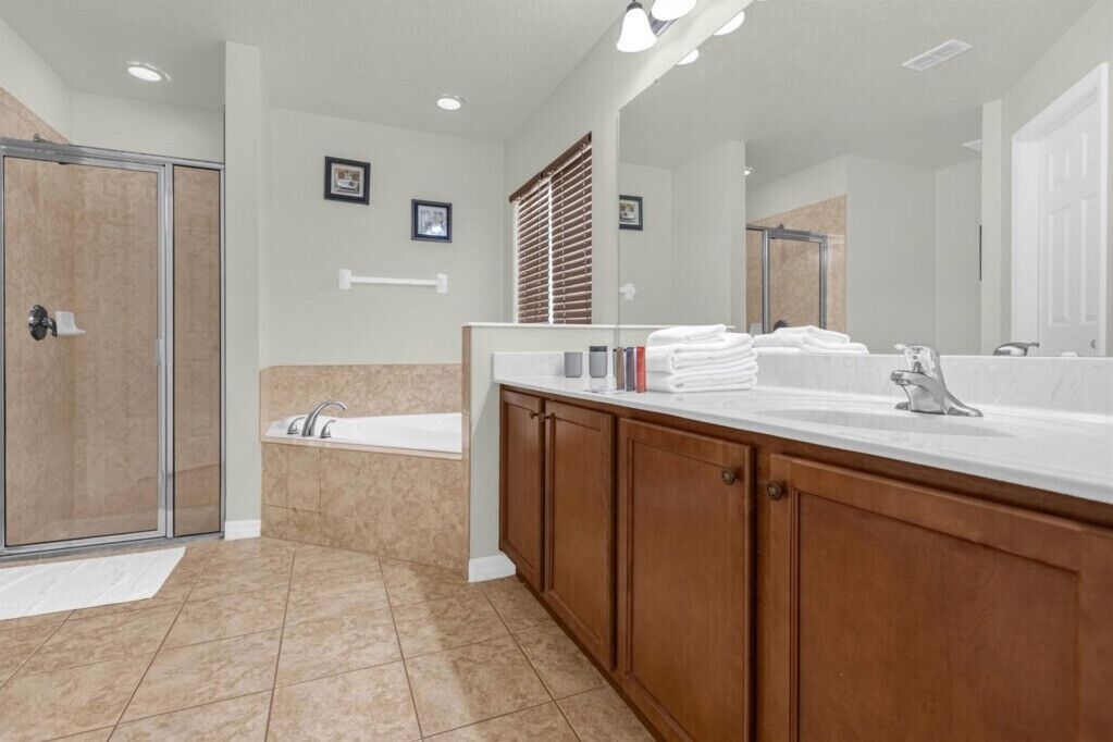 A modern bathroom with a large mirror, a bathtub, and a shower area.