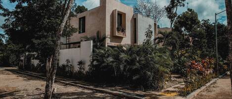 A modern building with a minimalist design, surrounded by lush greenery and a clear sky.