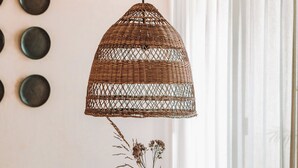 Een eettafel gedekt met borden, bestek en een vaas met gedroogde planten.