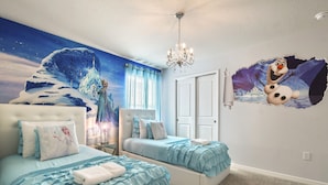 Un dormitorio con dos camas, una araña, un mural y un adhesivo de pared.