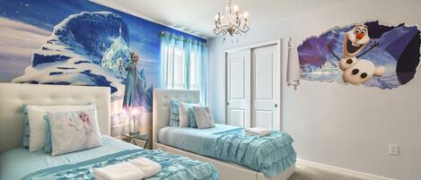 A bedroom with two beds, a chandelier, a mural, and a wall decal.