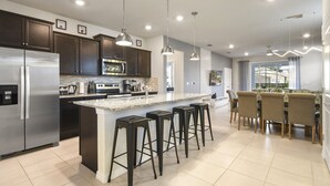 Una cocina moderna con una isla grande, taburetes de bar y un comedor con sillas.