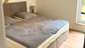 Ein Schlafzimmer mit einem großen Bett, einer Wanddekoration mit einer Schildkröte, einer Pendelleuchte und einem Fenster mit Blick ins Grüne.