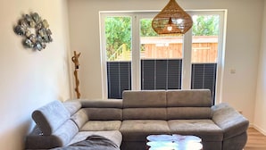 Ein Wohnzimmer mit Ecksofa, Couchtisch und großem Teppich.