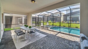 A modern patio with a glass enclosure, a pool, and a dining area with a table and chairs.