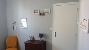 Ein Zimmer mit Tür, einem Schrank, einem Stuhl und Bildern an der Wand.