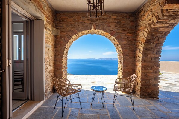 Relax in a serene outdoor space with a scenic view, a stone archway, and comfortable seating for two.