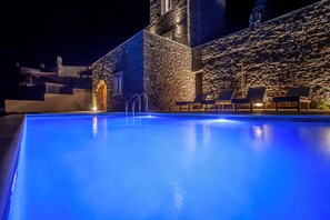 Relax by the illuminated pool, surrounded by lounge chairs and a tranquil atmosphere.