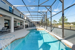 A swimming pool with a glass enclosure, outdoor seating, and a view of the surrounding area.