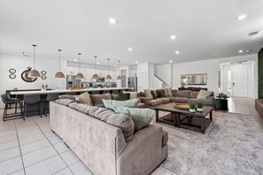 A modern living room with a sofa, coffee table, and a kitchen area with a bar.