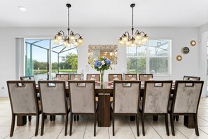 A dining area with a large table, multiple chairs, and a chandelier.