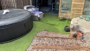 Eine Terrasse mit schwarzen Sitzsäcken, Korbmöbeln und einem kleinen Tisch mit Dekoration.