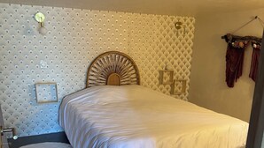 Ein Schlafzimmer mit einem Bett, zwei runden Teppichen, einem dekorativen Kopfteil und einer Wandleuchte.