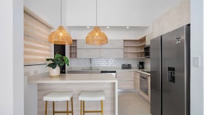 A modern kitchen with a central island, two bar stools, a refrigerator, and pendant lights. - Sophisticated Home with a Chic Design and a Private Terrace with a Plunge Pool (Sardinal)