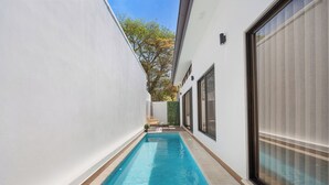 A narrow swimming pool with a tiled deck, surrounded by white walls and a large window on one side. - Sophisticated Home with a Chic Design and a Private Terrace with a Plunge Pool (Sardinal)