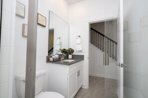 Ein modernes Badezimmer mit Toilette, Waschbecken und Spiegel. Eine Treppe führt zu einer anderen Ebene.