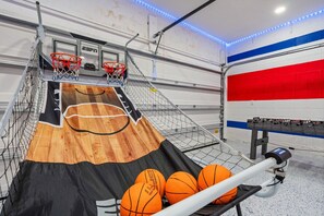 Un terrain de basket avec des paniers, un plancher en bois et une table où sont rangés les ballons.