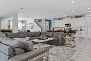 Un salon moderne avec un canapé d’angle, une table basse et un coin repas comprenant une table et des chaises en verre.