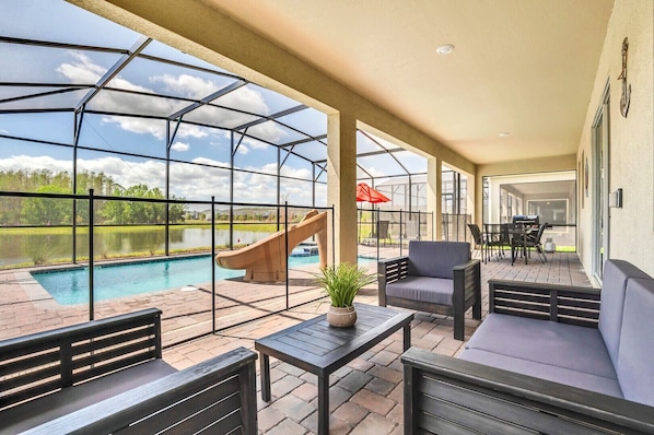 A covered outdoor area with a pool, seating, and a slide.