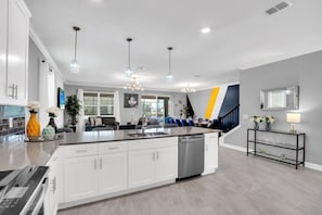 A modern kitchen with a central island, white cabinetry, and pendant lighting.