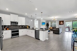 A modern kitchen with white cabinets, a central island, and stainless steel appliances.