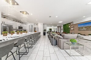 A modern kitchen with a long island, bar stools, and a dining area with a sofa and coffee table. - Last Minute Disney Getaway! Luxury Villa with Private Pool. Book Now! #115463 (Orlando)