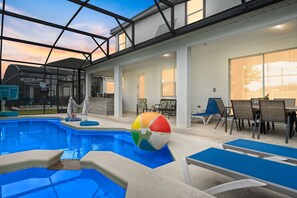 Una piscina interior con sillones de descanso y una mesa, rodeada por un porche cubierto.