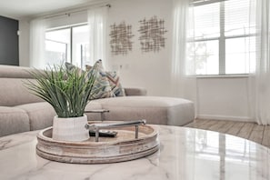 A modern living room with a marble coffee table, a potted plant, and a sofa.
