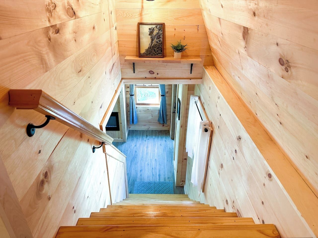 Interno in legno con una scala che conduce a una stanza con finestra e tende.