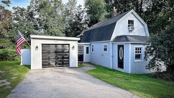 Een tweelaags huis met een garage, een voortuin en een kleine aangebouwde schuur.