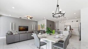 Una cocina moderna con armarios blancos, una isla grande y un área de comedor con un sofá y sillas grises.