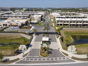 An aerial view of a modern residential complex with multiple buildings, a central road, and landscaped areas with palm trees. - Last Minute Disney Getaway! Villa with Private Pool & Hot Tub. Book Now! #107761 (Orlando)