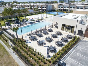 A rooftop pool area with multiple lounge chairs and tables, surrounded by a low fence and palm trees. - Last Minute Disney Getaway! Villa with Private Pool & Hot Tub. Book Now! #107761 (Orlando)
