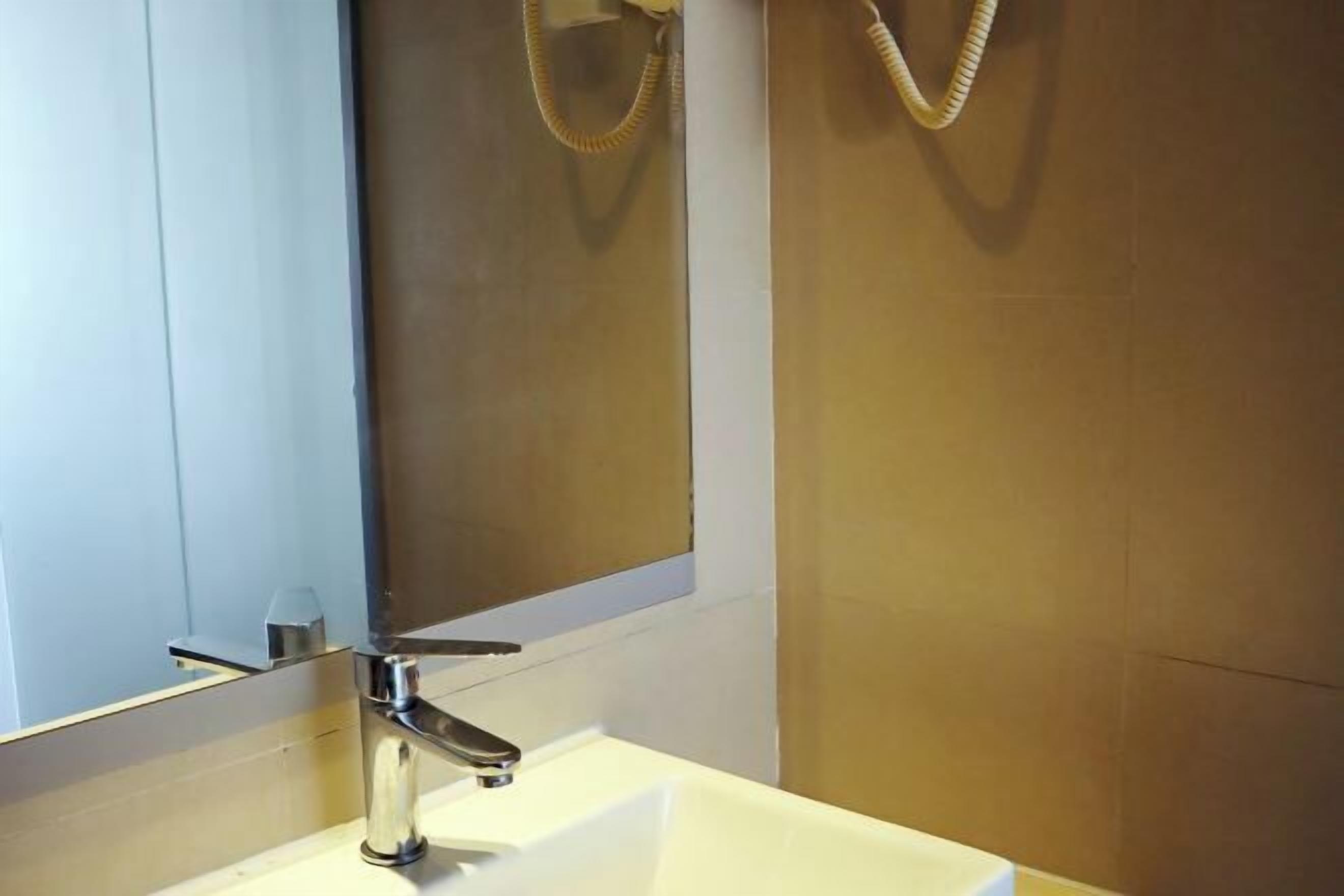 Une salle de bain avec un lavabo blanc, un robinet chromé et un miroir.