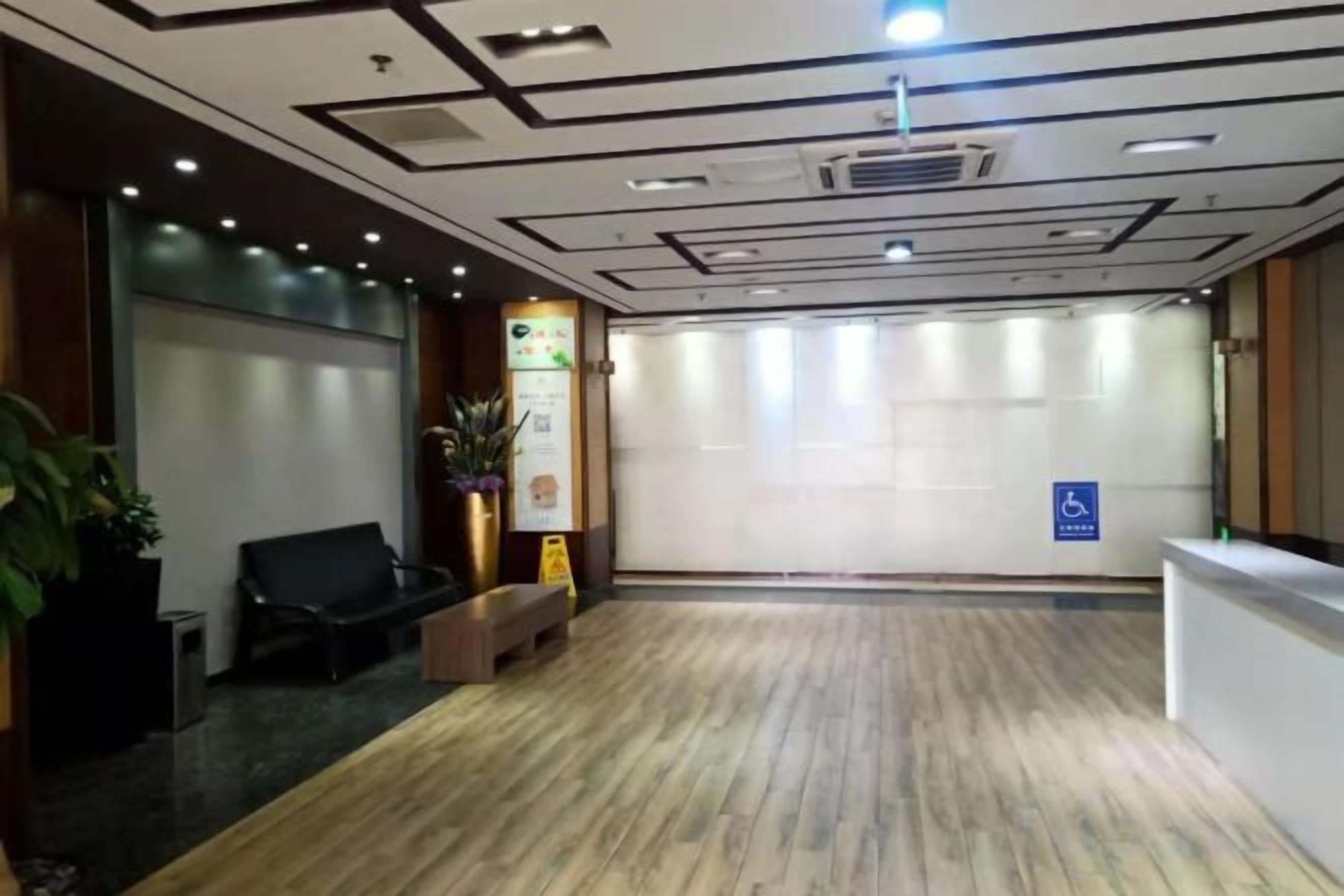 A reception area with a wooden floor, a reception desk, a bench, and a wheelchair-accessible sign.