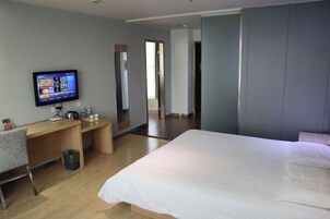 A modern hotel room with a large bed, a desk, and a television.